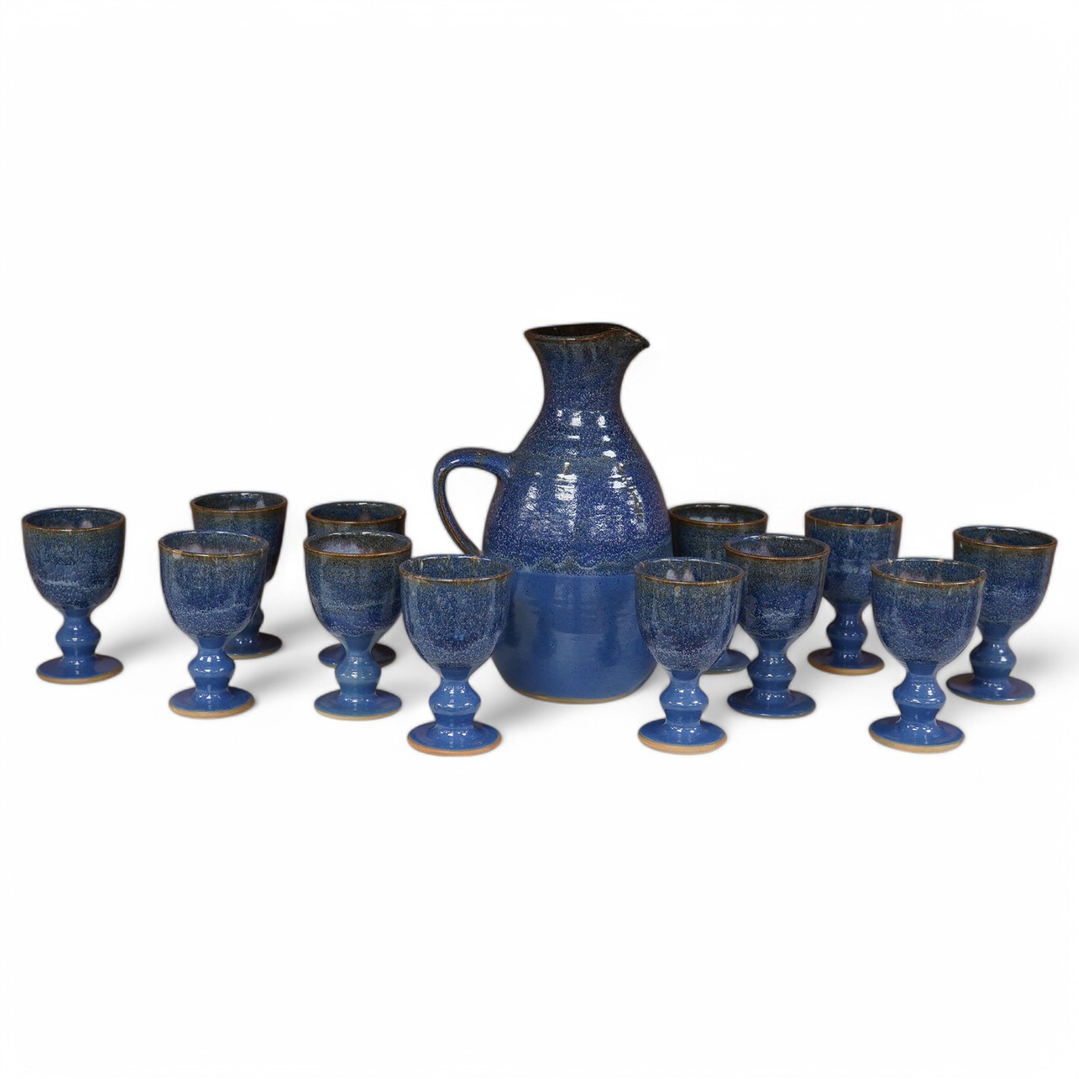 A Canterbury pottery, blue glaze jug and twelve goblets, jug 28cm high. Condition - fine chip to one goblet